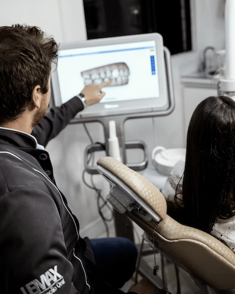 a dental practitioner educating his patient about her teeth during consultation