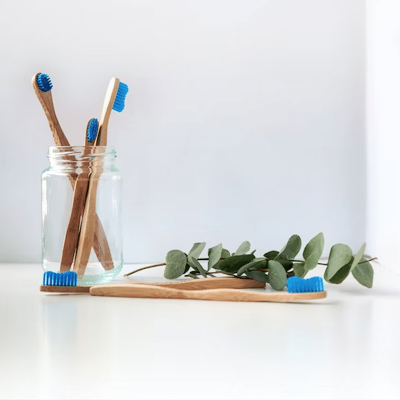 some toothbrush with blue bristles  and wooden handle inside a clear jar