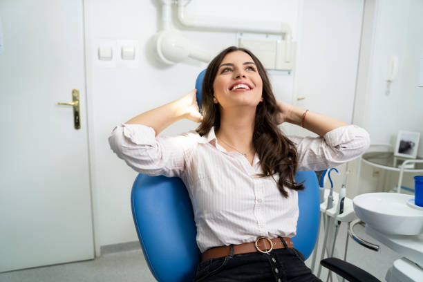 a woman smiling while sitting on a dental chair