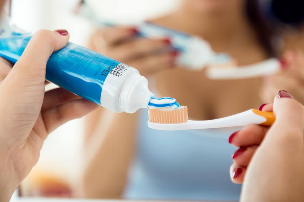 a hand putting some toothpaste on a toothbrush