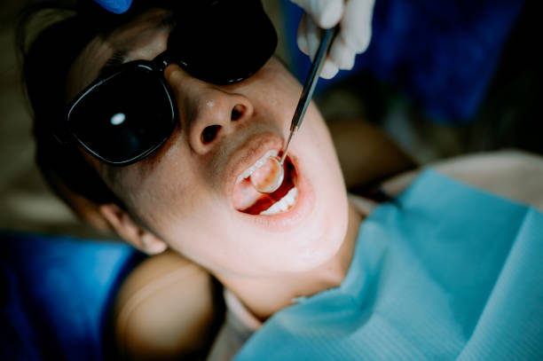 a dental professional examining a patient's mouth using a dental mirror