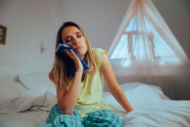 a woman holding a cold compress to her jaw due to tooth pain