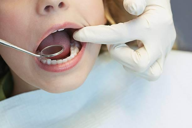a young child in a dentist's chair as a dental professional gently examines their molars